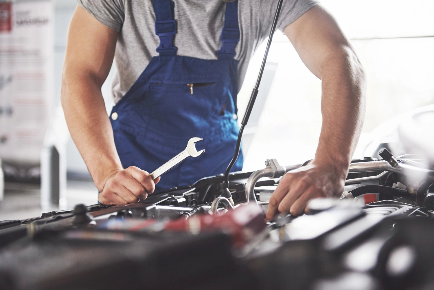 Fuhrparkservice Mobil14 – Beratung, Planung & Wartung für Nutzfahrzeugflotten – Ein Mechaniker in blauem Overall arbeitet in einer Werkstatt an einem Automotor. Fuhrparkservice Mobil14 – Beratung, Planung & Wartung für Nutzfahrzeugflotten –